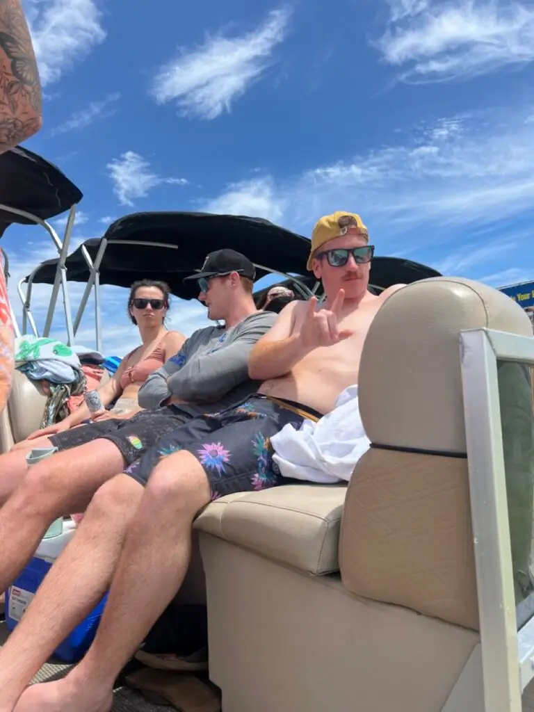 A Bro giving a peace sign while relaxing at crab island after renting a pontoon boat with peak's pontoons